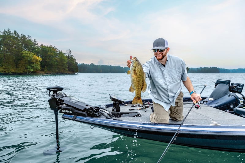 An angler smiles as holds his fish insider a boat outfitted with Garmin electronics.