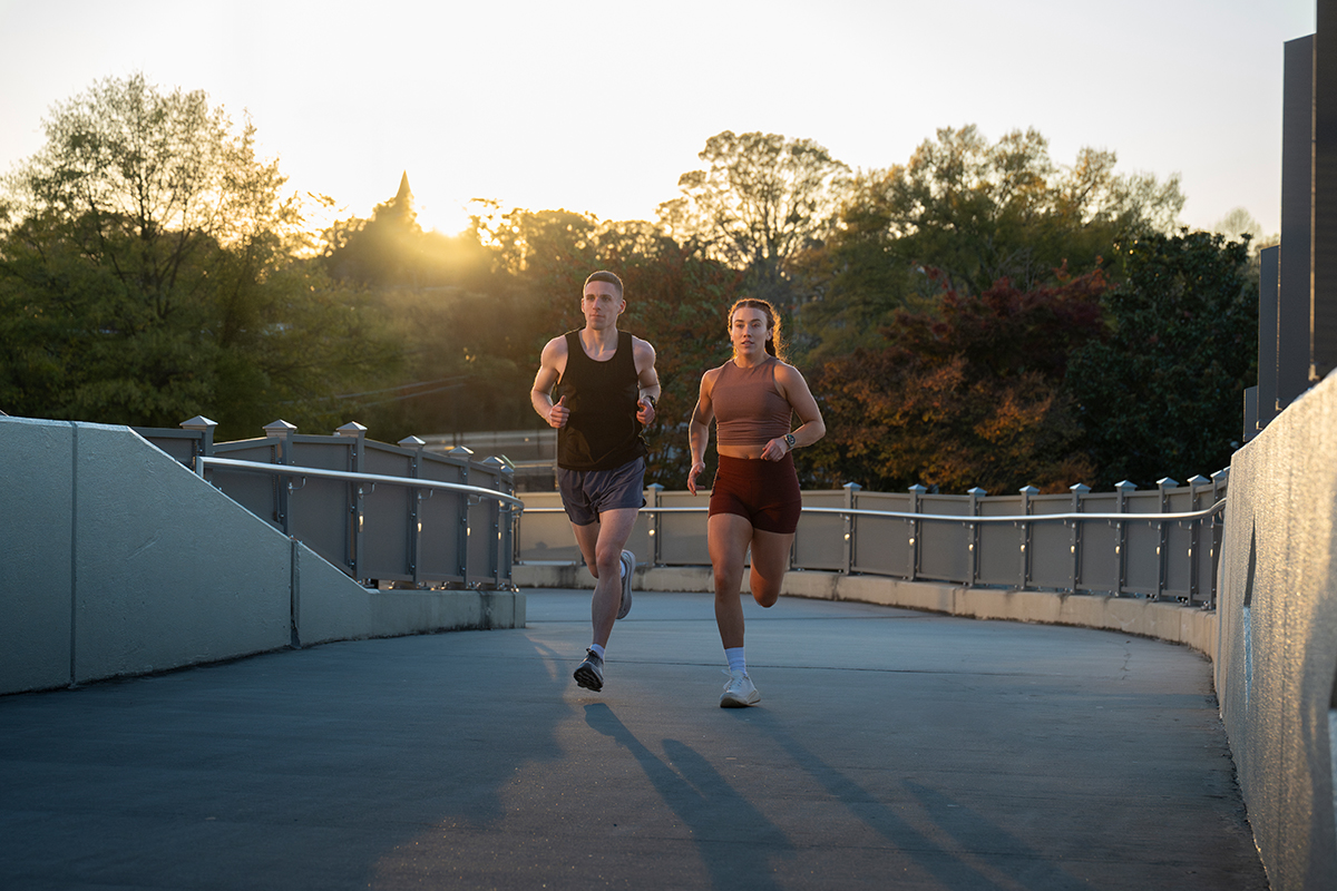 A man and woman wearing Garmin smartwatches run along a path.