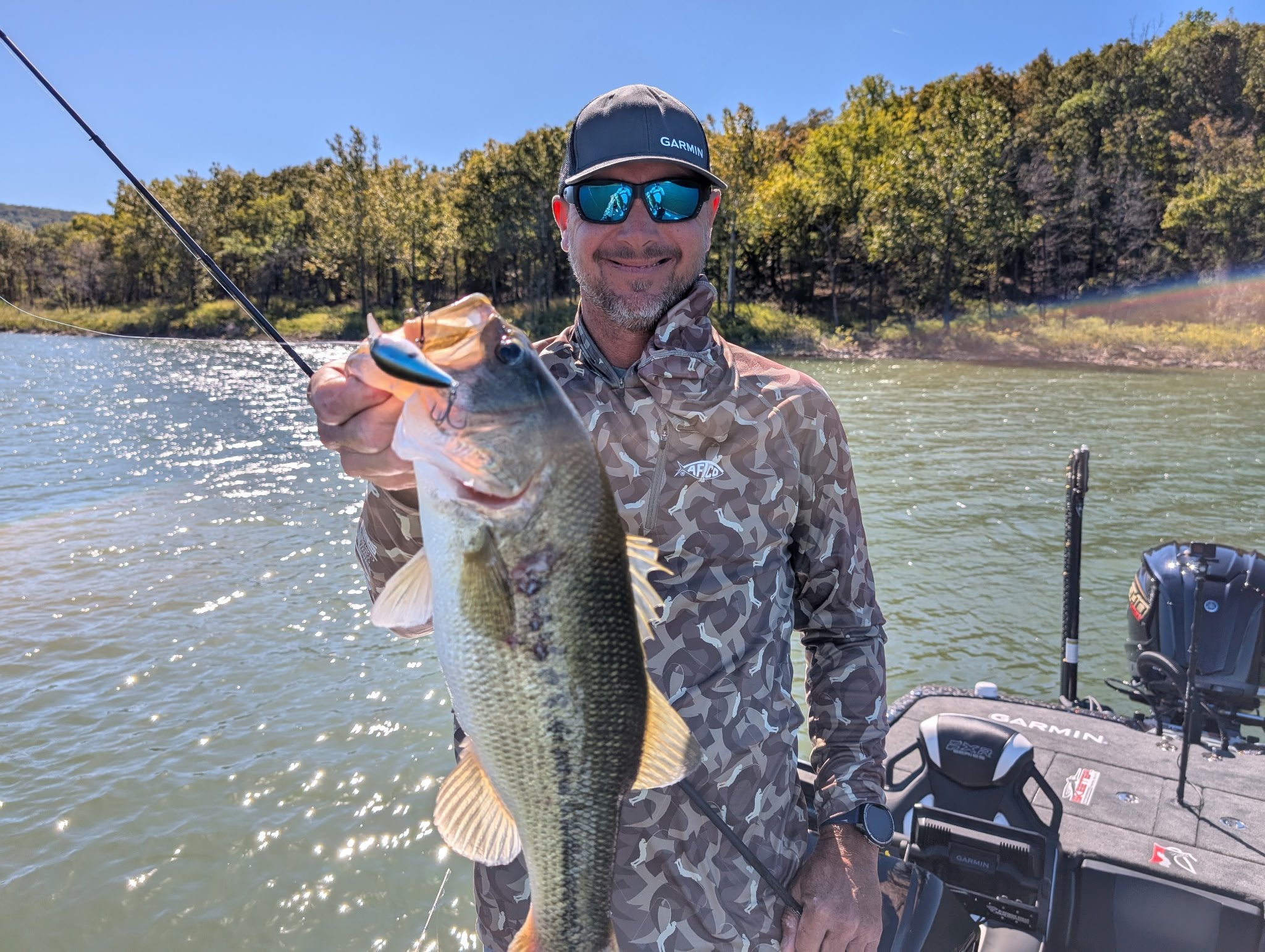 Jason Christie smiling and holding a fish while on his boat.