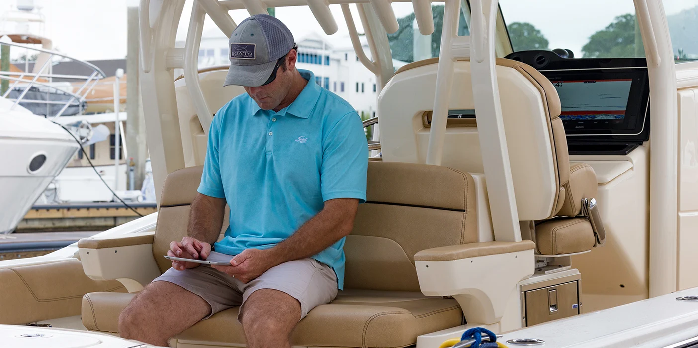 Man sitting on his boat looking down at his mobile device.