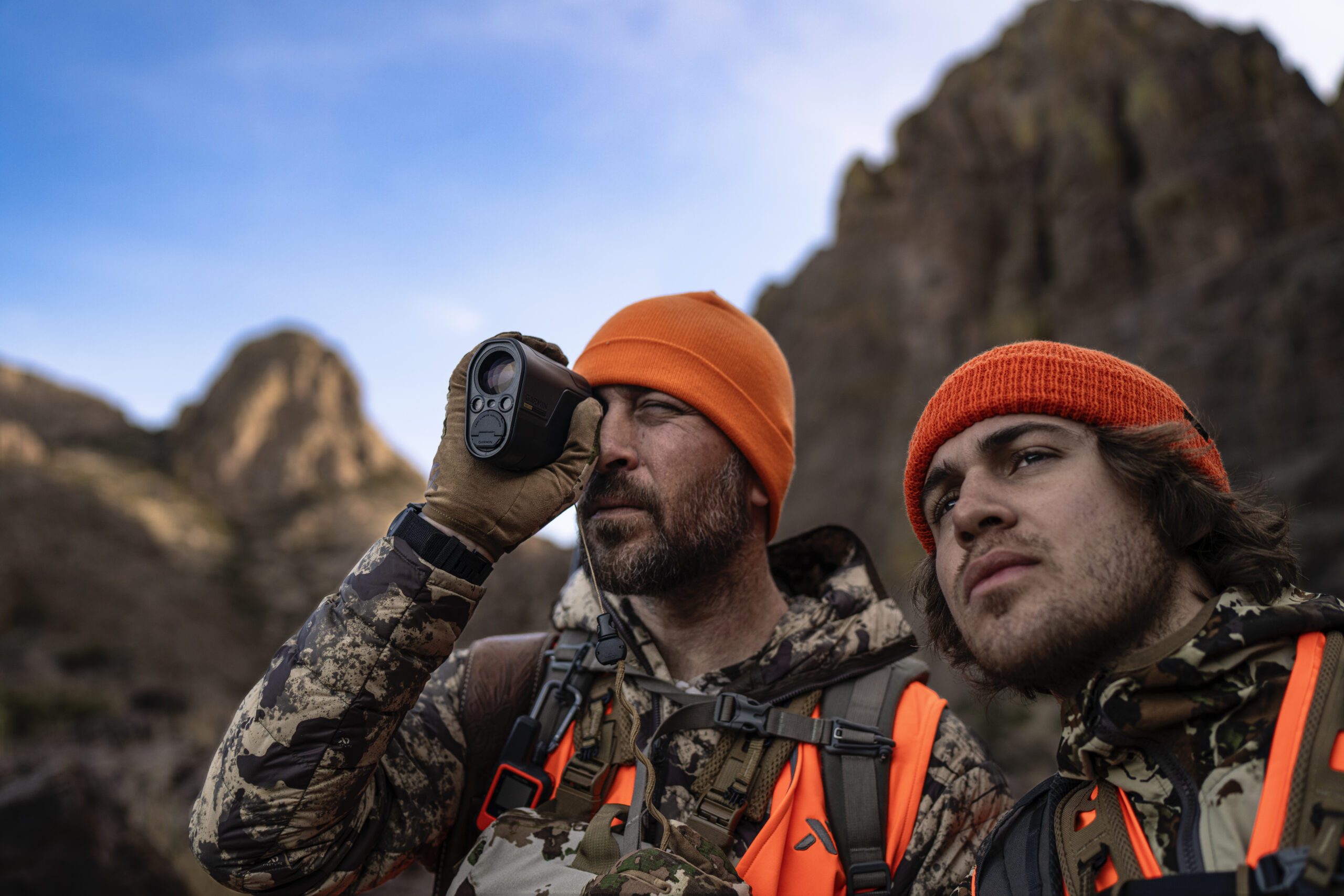 One man looking into the distance while the other looks into the L60i rangefinder. Both are in hunting gear.