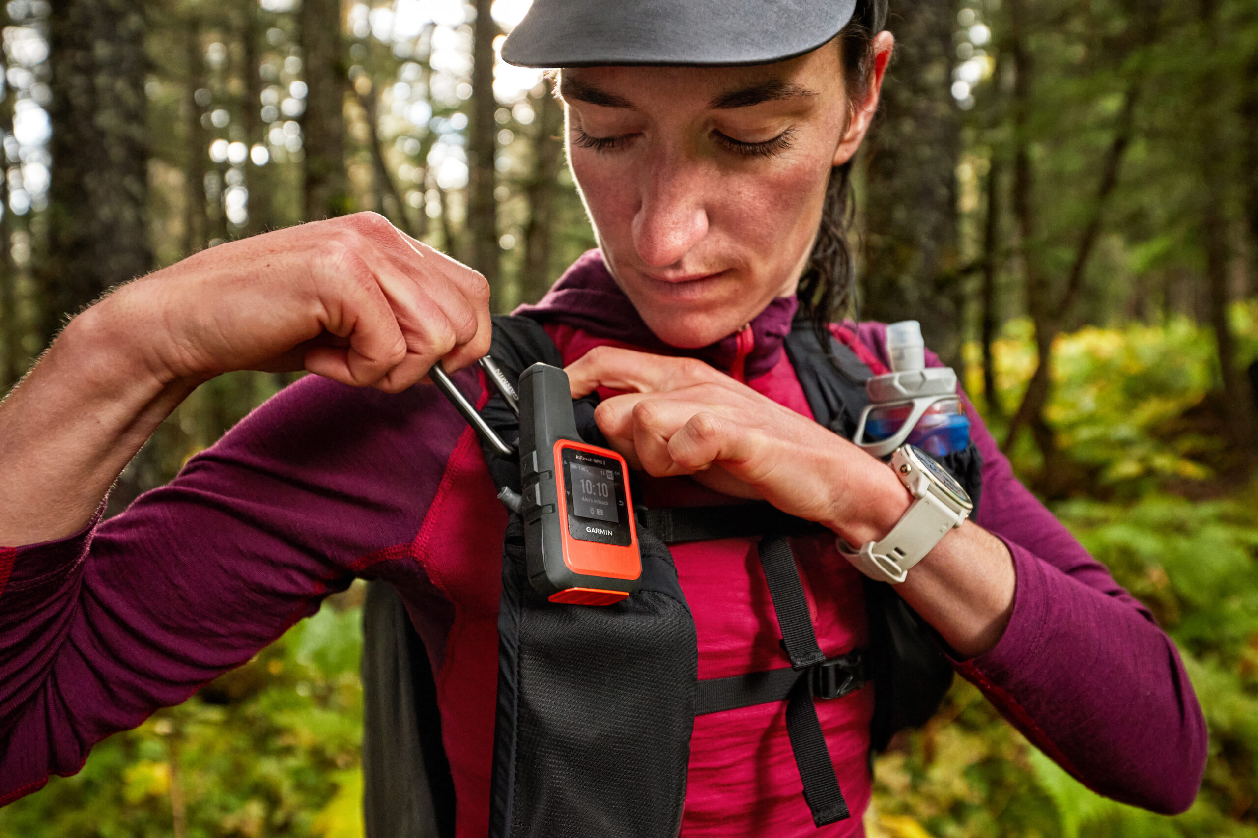 A woman have an Garmin inReach mini 2 Satellite Communicator with her during her outdoor activity. She also wears a Garmin outdoor watch on her wrist.