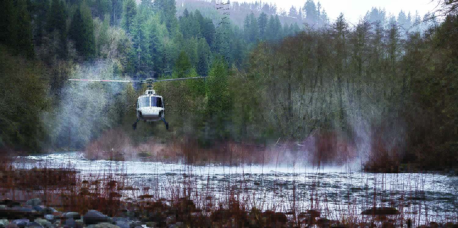 Helicopter hovering over river in backcountry