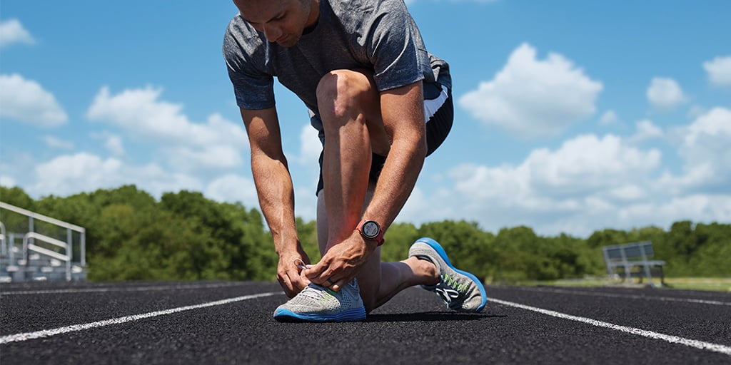 Man tying shoe on a track