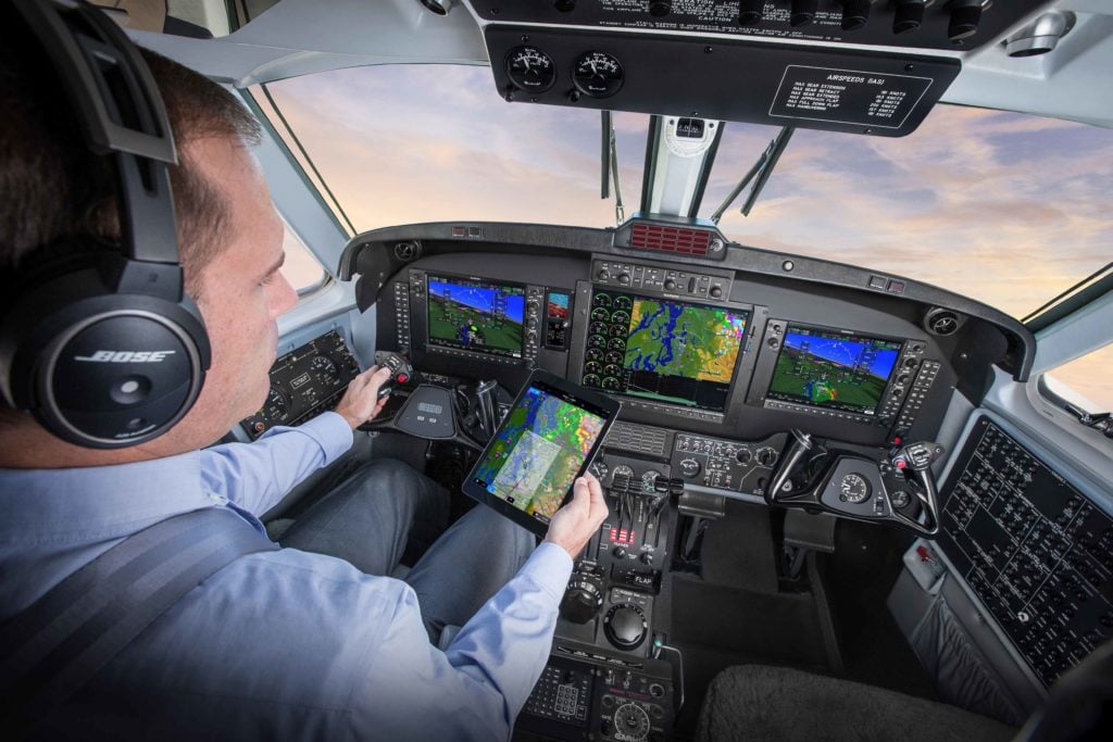 King Air flight deck featuring G1000 NXi, pilot holding iPad