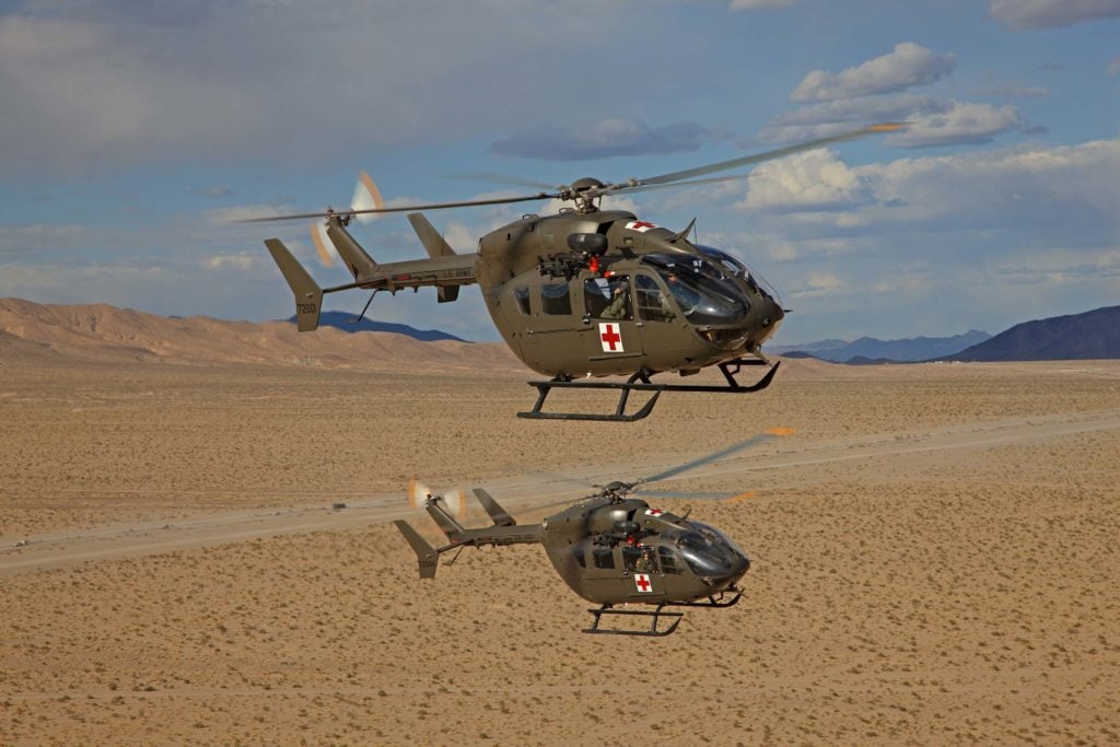 Two Airbus helicopters flying in formation over desert