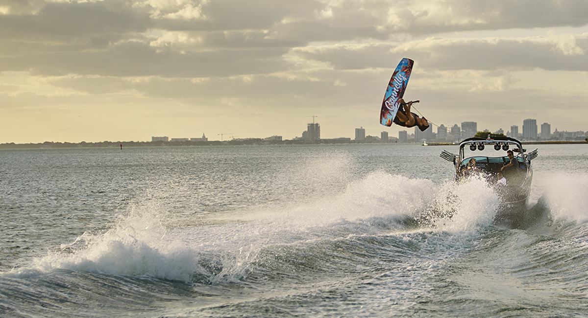 An airborne wake boarder trails behind a boat in the ocean.