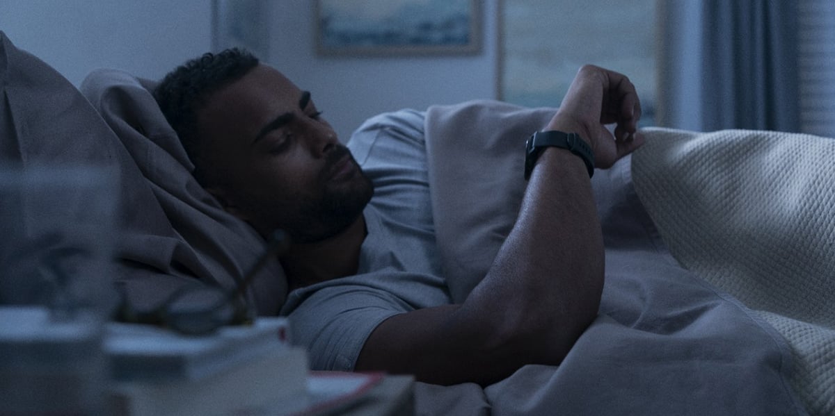 Picture of man checking his Garmin smartwatch before sleeping.