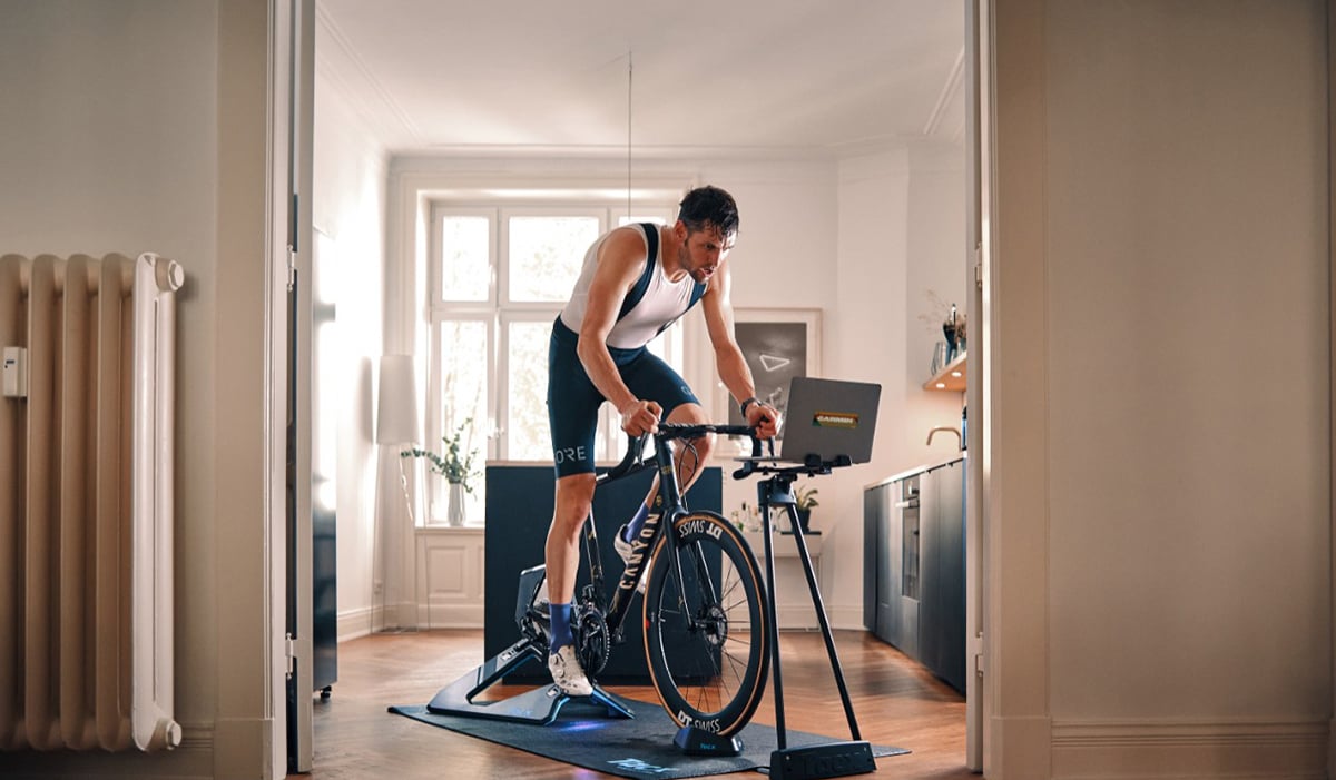 A man rides a bike on a Garmin indoor smart bike trainer.