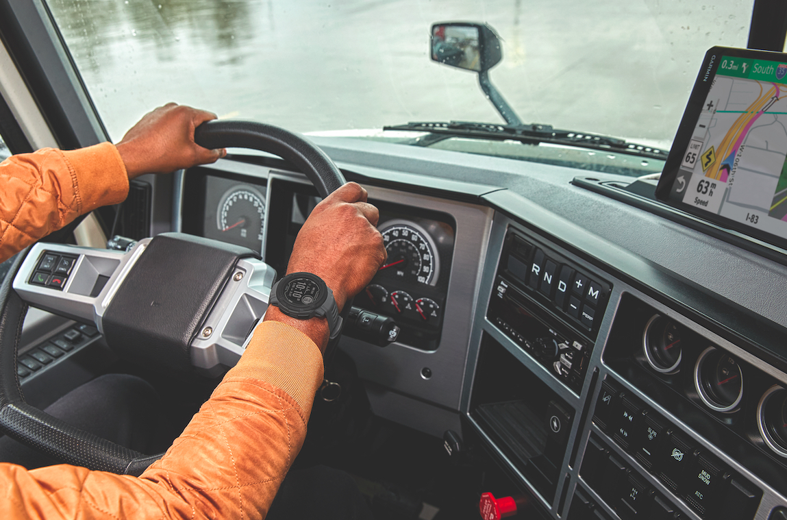Picture of trucker behind the wheel, and wearing his Instinct 2 dezl smartwatch.