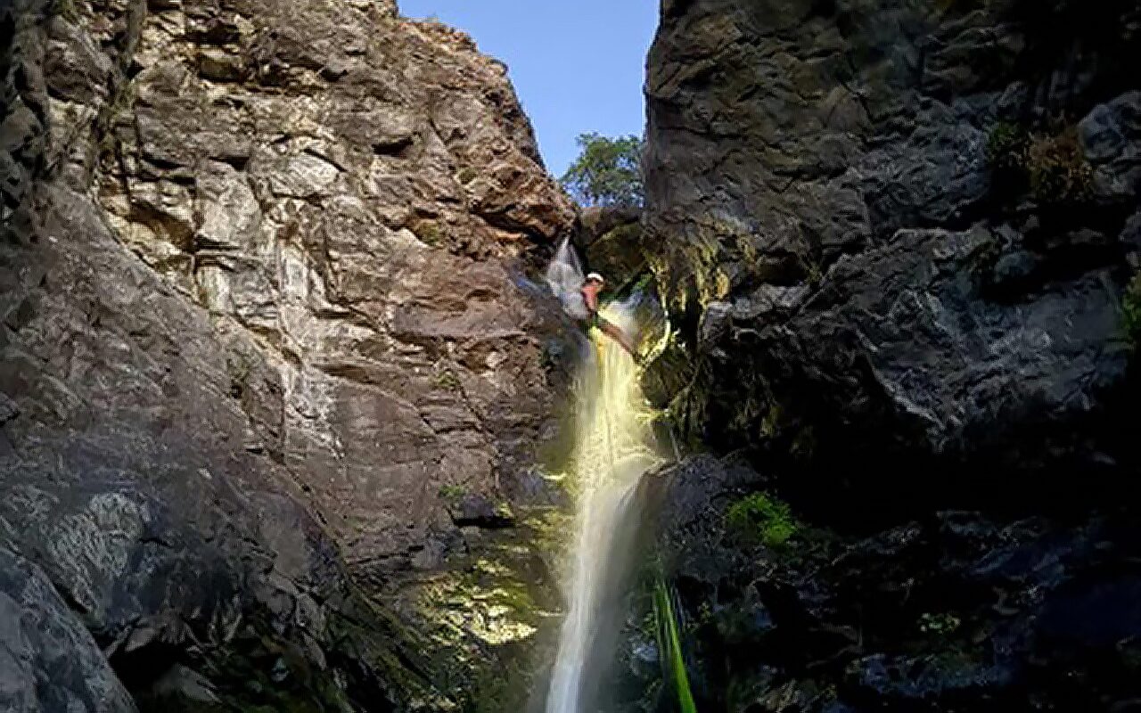 Une personne monte dans une cascade d'eau en via ferrata