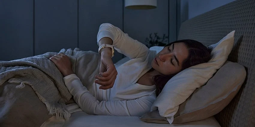 woman in bed at night checking smartwatch