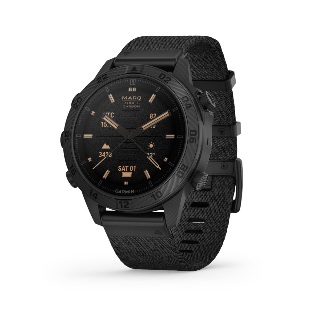 En högupplöst bild av Garmin Marq Carbon Commander-klockan med en svart urtavla och digital display. Klockan har en kolfiberdesign och visar en statyikon på displayen, vilket indikerar en specialfunktion för utomhus- och äventyrsaktiviteter.