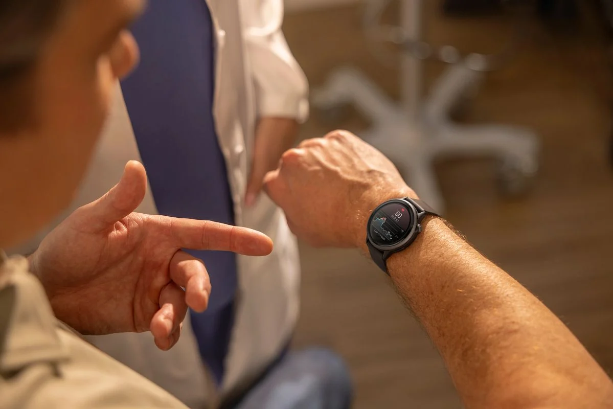 Person visar hälsodata på en Garmin-smartwatch i samtal med vårdpersonal